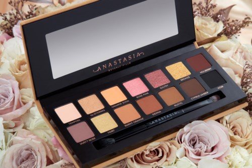 Eine Lidschattenpalette mit 12 Farben, auf Blumen mit Spiegel und Pinsel.