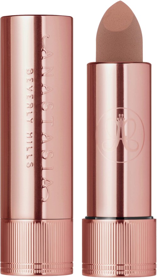 A makeup concealer stick in a shiny rose gold tube with a cap. The brand name is on the packaging.