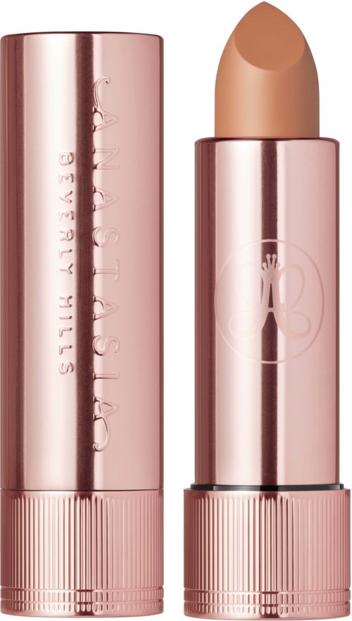 Ein hellrosa Lippenstift-Stift neben dem geöffneten Lippenstift, der die beige Farbe zeigt.