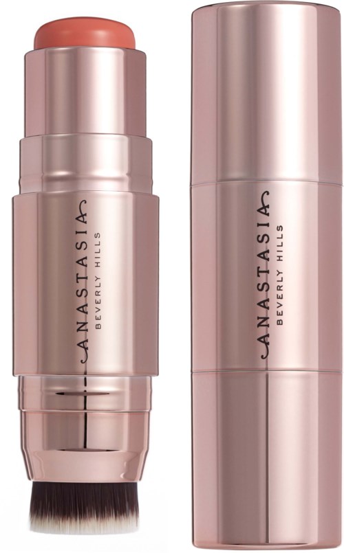 Vaaleanpunainen meikkitanko harjalla, jonka päällä lukee 'Anastasia Beverly Hills', vieressä samanlainen sylinterimäinen rasia.