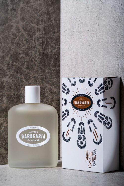 En frostet glassflaske med hvit kork og en eske med svarte skosåler og en logo.