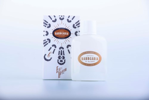 A white bottle with a label and a box, both with black patterns and brown text. They appear to be grooming or beauty products.