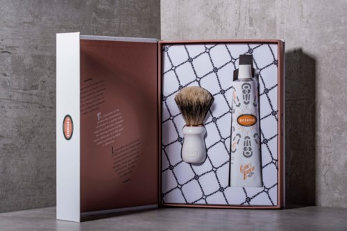 A grooming kit with a shaving brush and electric trimmer in a box, designed for beard care.