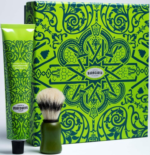 En grønn gaveeske med tilsvarende tube og barberhøvelkost, alle med svarte og grønne mønstre. Esken har en etikett som sier "Barbearia."