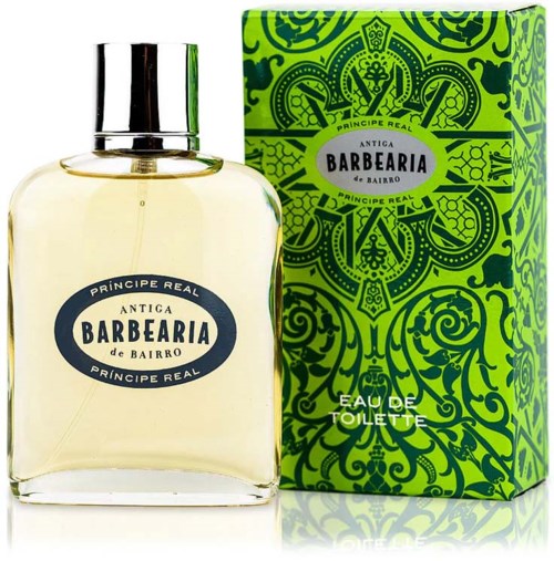 A perfume bottle and box with green and black intricate patterns and labels. The bottle is transparent with pale liquid inside.