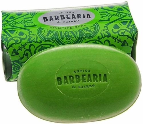 A green soap with the words "Antiga Barbearia de Bairro" embossed on it and colorful box packaging.