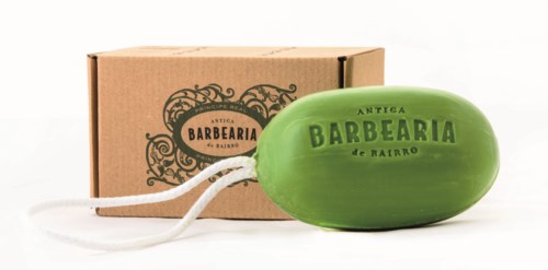 A green soap bar with black text and a brown cardboard box with decorative black design.