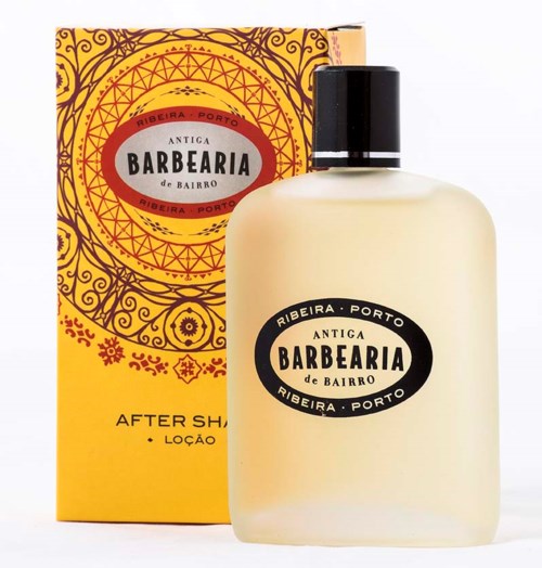 Eine weiße Flasche mit schwarzem Deckel, beschriftet "Antiga Barbearia de Bairro". Die Box ist gelb und orange mit Dekormustern.