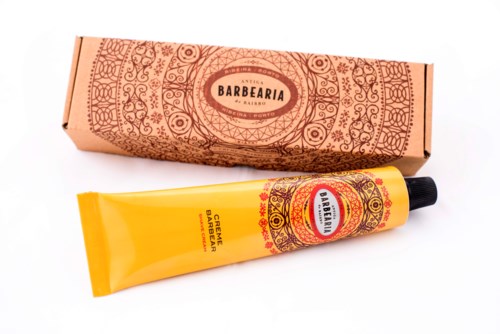 Das Bild zeigt eine Tube Bartcreme und eine dekorative Pappschachtel mit detaillierten Mustern.
