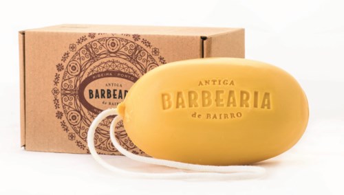 Keltainen saippua ja naru, molemmat on merkitty 'Antiga Barbearia de Bairro' ja niissä on koristeellisia kuvioita.