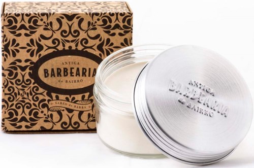 A jar of white cream with a metal lid and a decorative brown box with a label. The label says 'Antiga Barbearia do Bairro.'