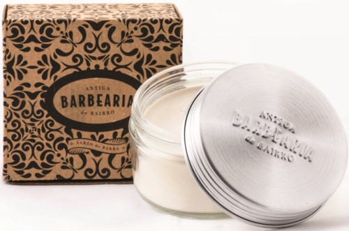A jar of white cream in front of a decorative cardboard box with a lid nearby. The box has a fancy design and label.
