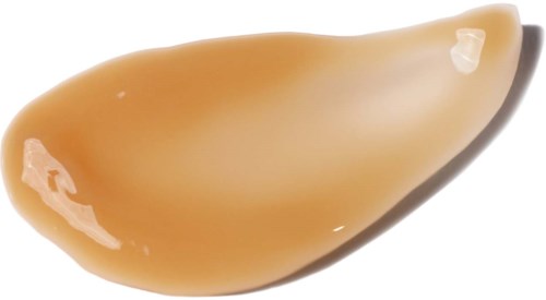 Ein kleiner Tropfen hellbraune Flüssigkeit mit glänzender Oberfläche und leicht spitzer Form.