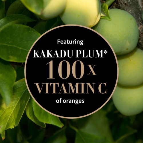 Ein runder Aufkleber besagt, dass Kakadu-Schlehe 100-mal mehr Vitamin C hat als Orangen. Grüne Früchte und Blätter sind im Hintergrund.