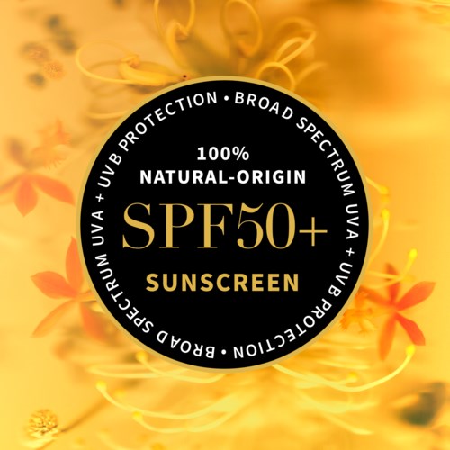 Ein runder Aufkleber bewirbt SPF50+ Sonnenschutz mit breitem UV-Schutz und natürlichen Inhaltsstoffen, vor Blumenhintergrund.