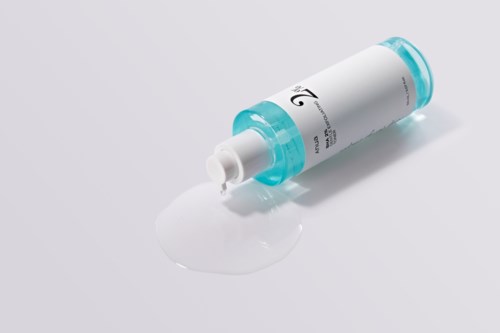Een witte crème of lotion is uit een kleine tube met blauwe dop op een witte ondergrond gemorst.