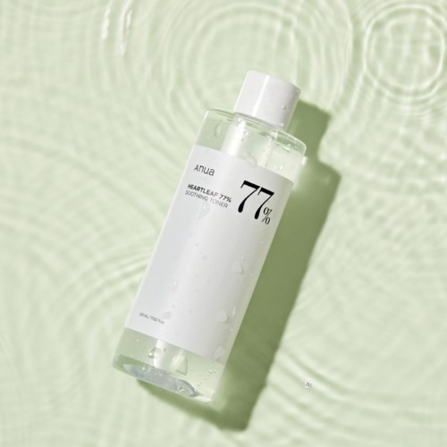 Een heldere tonerfles met witte label op een lichtgroene textured achtergrond, met waterdruppels.