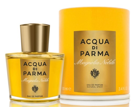 Ein Parfümflasche und eine passende zylindrische Box, beide gelb mit goldenen und schwarzen Etiketten, mit dem Text 'Acqua di Parma Magnolia Nobile.'