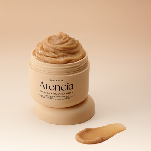 Eine cremefarbene Dose mit Arencia Banderole, gefüllt mit dicker beige Creme und etwas Creme ausgelaufen.