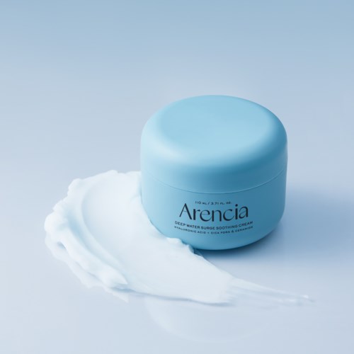 Ein blauer Behälter mit Gesichtspflegecreme und etwas Creme auf hellem Hintergrund.