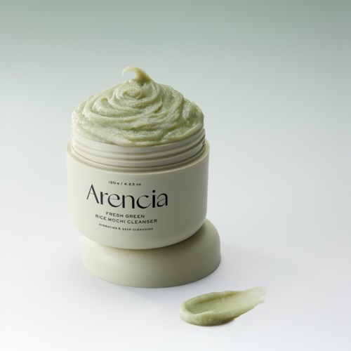 Ein Behälter mit grüner Gesichtspflegecreme, etwas Creme außen, einfacher weißer Hintergrund.
