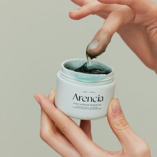 Eine Person hält ein Glas mit grünem Gel und taucht den Finger hinein.