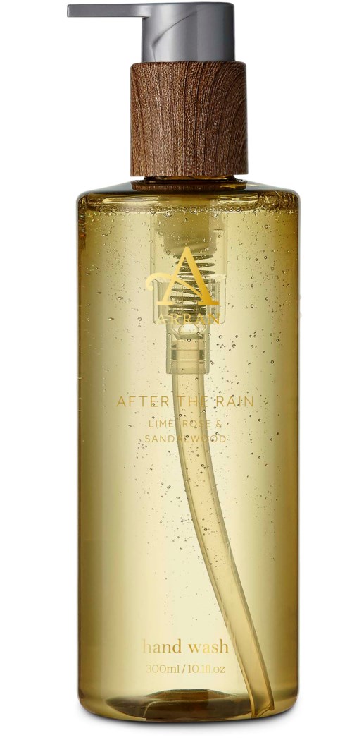 Eine gelbe Flüssigkeit Handwäsche in einer transparenten Flasche mit Holz- und Silberechnungszapfen, enthält kleine Blasen.