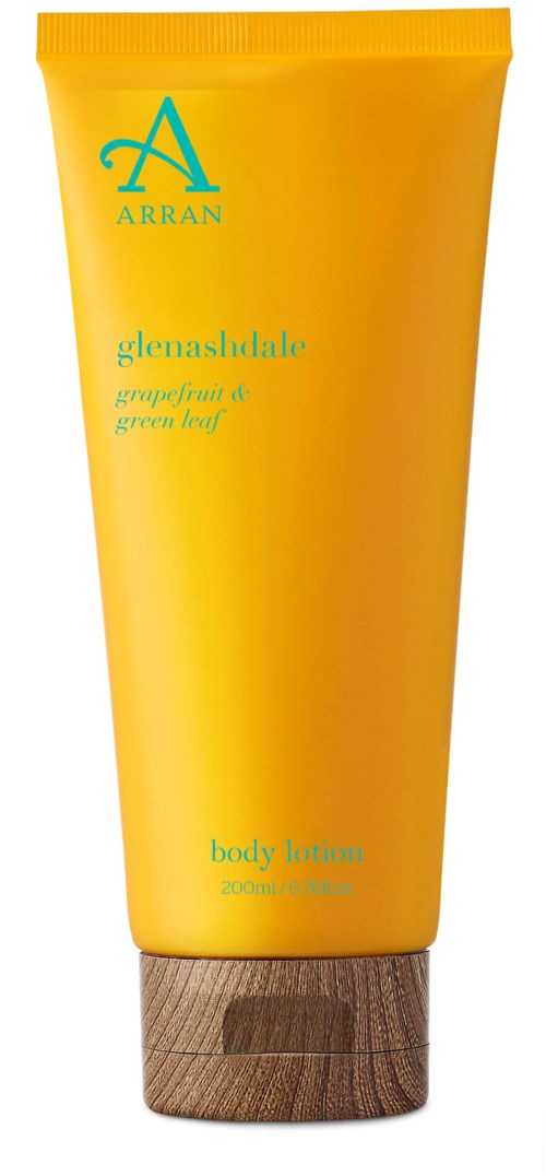 Eine gelbe Tube mit Körperlotion von Arran, beschriftet mit Glenashdale-Extrakten, steht auf einer Holzunterlage.