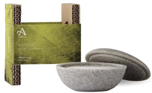 Seife und Seifenschale in Steinform, mit grüner Verpackung im Hintergrund.