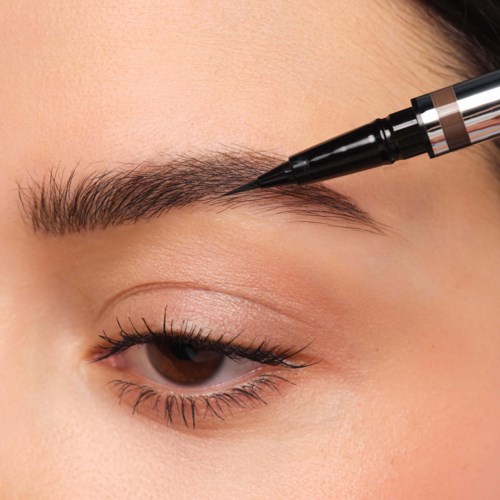 Eyeliner-pen som påfører en mørk linje langs øvre øyelokk på en persons øye. Nærbilde av øyenmakeup.