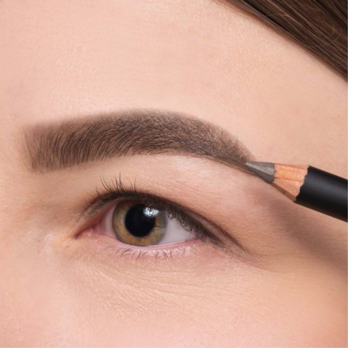 Eine Person füllt ihre Augenbraue mit einem Bleistift für Make-up aus. Die Augenbraue sieht gut geformt und dick aus.