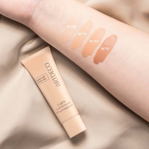Swatches of four different shades of foundation on a person's arm, with a tube of foundation below. The shades are labeled N°08, N°14, N°22, and N°31.