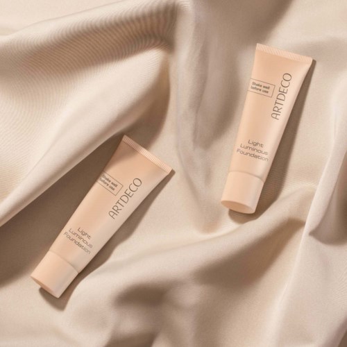 Två tuber av Artdeco Light Luminous Foundation på krämfärgat tyg.