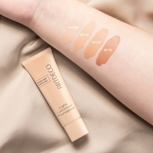 Foundationprov i fyra nyanser på arm, med en tub av foundation märkt 'Artdeco Light Luminous Foundation' i närheten.
