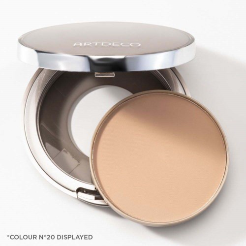 Een compacte make-updoos met poeder erin, gemarkeerd 'COLOUR N°20 DISPLAYED', met een zilveren deksel en beige poeder.