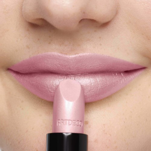 Nahaufnahme der Lippen mit hellrosa Lippenstift, Finger berührt Lippen, glatte Haut, Teil der Nase sichtbar.