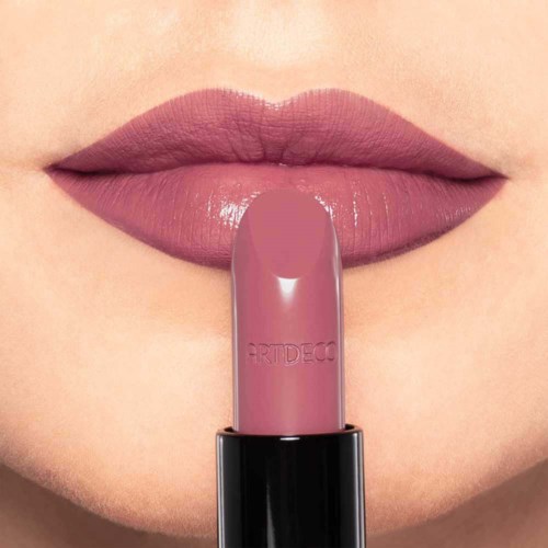 De lippen van een persoon zijn matroosroze, met een bijpassende lippenstift vastgehouden onder de lippen.