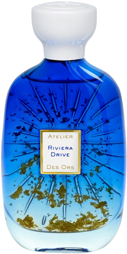 A blue glass bottle with a white cap and a label that says "Atelier Riviera Drive Des Ors."