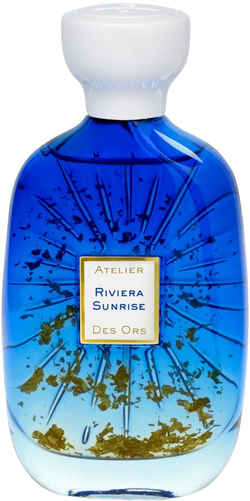 A blue glass bottle with a white cap, decorated with gold and blue details, labeled 'Atelier Riviera Sunrise Des Ors'.