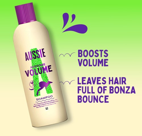 A shampoo bottle with purple cap, green background, and text about boosting volume and making hair bounce.