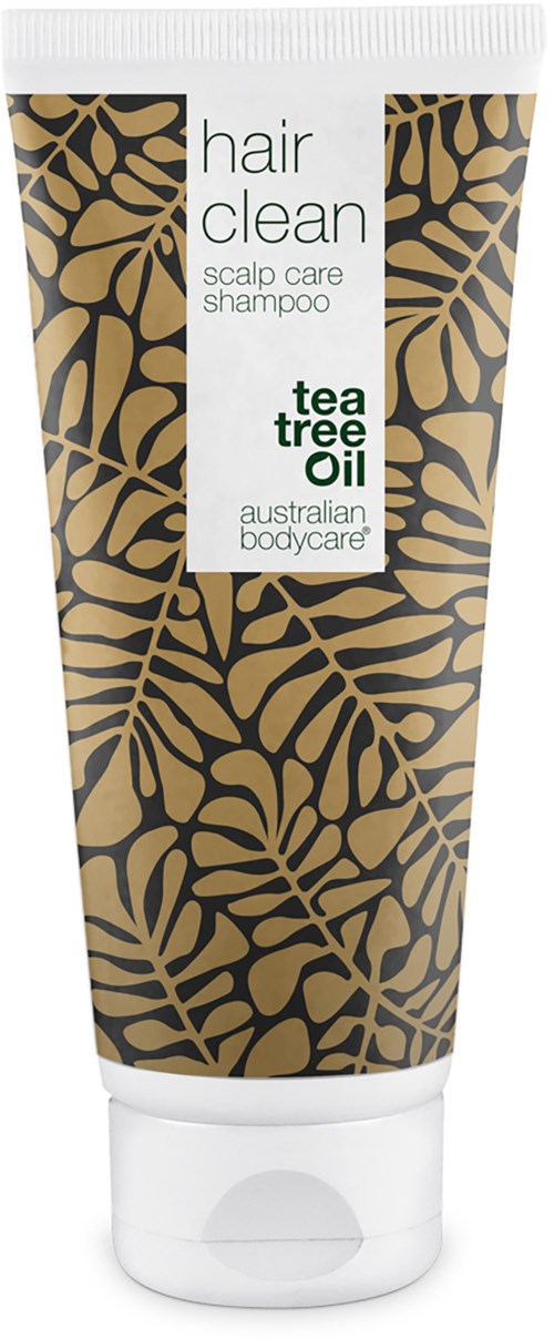 En tub med schampo med svart och guld lövdesign, märkt 'hair clean' med tea tree oil för hårbottenvård.