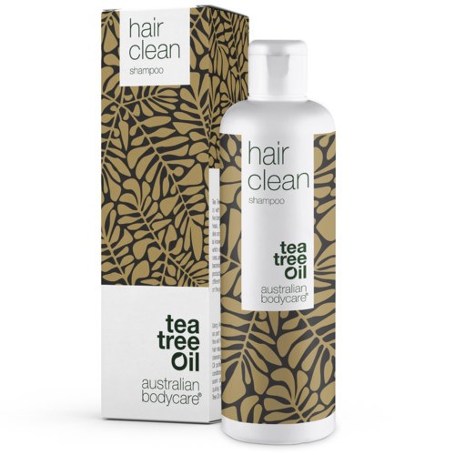 En vit schampoflaska med matchande förpackning, med svart och guldbladdesign och text om tea tree oil.