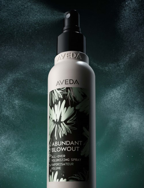 Eine silberne Flasche Aveda Abundant Blowout Spray mit schwarzem Deckel und Blumenmuster-Beschriftung.