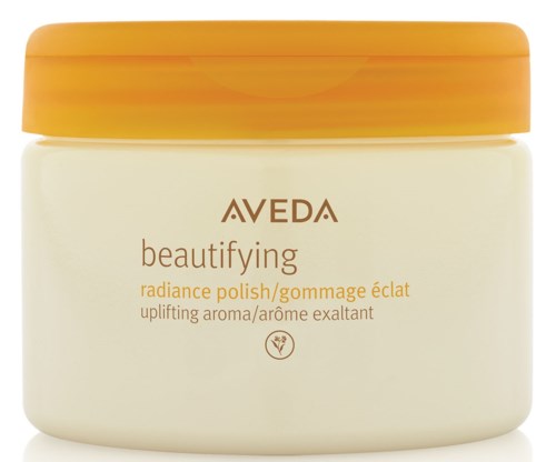 Een pot met Aveda beautifying radiance polish met geel-oranje deksel en wit lichaam.