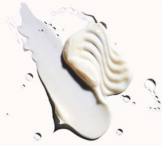 Eine weiße Seifenform in Muschelform liegt auf einem weißen Hintergrund mit Wassertröpfchen.
