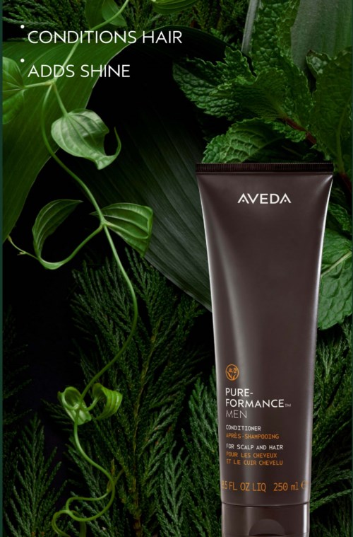 En mørk brun Aveda Pure-Formance Men sjampo- og hårbalsamflaske mot grønne blader med tekst om hårforhold og glans.