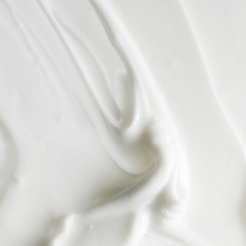 Nahaufnahmen einer glatten, cremigen weißen Substanz, möglicherweise Joghurt oder saure Sahne, mit geschwungener Textur.