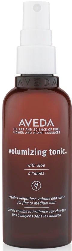 Eine braune Sprühflasche mit weißem Pumpkopf, beschriftet als Aveda volumizing tonic mit Aloe für Haare.