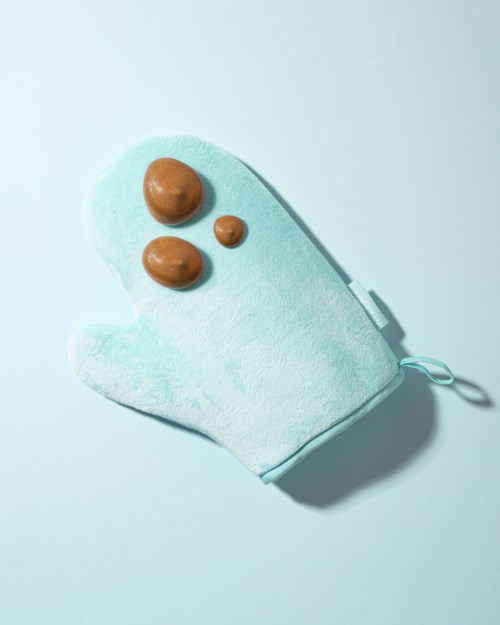 Ein hellblauer Ofenhandschuh mit drei braunen Flecken, liegt auf hellem Hintergrund.