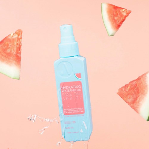 Blasdose mit Aufschrift 'Hydrating Watermelon Face & Body Mist' und Wassermelonenscheiben um sie herum auf rosa Hintergrund.